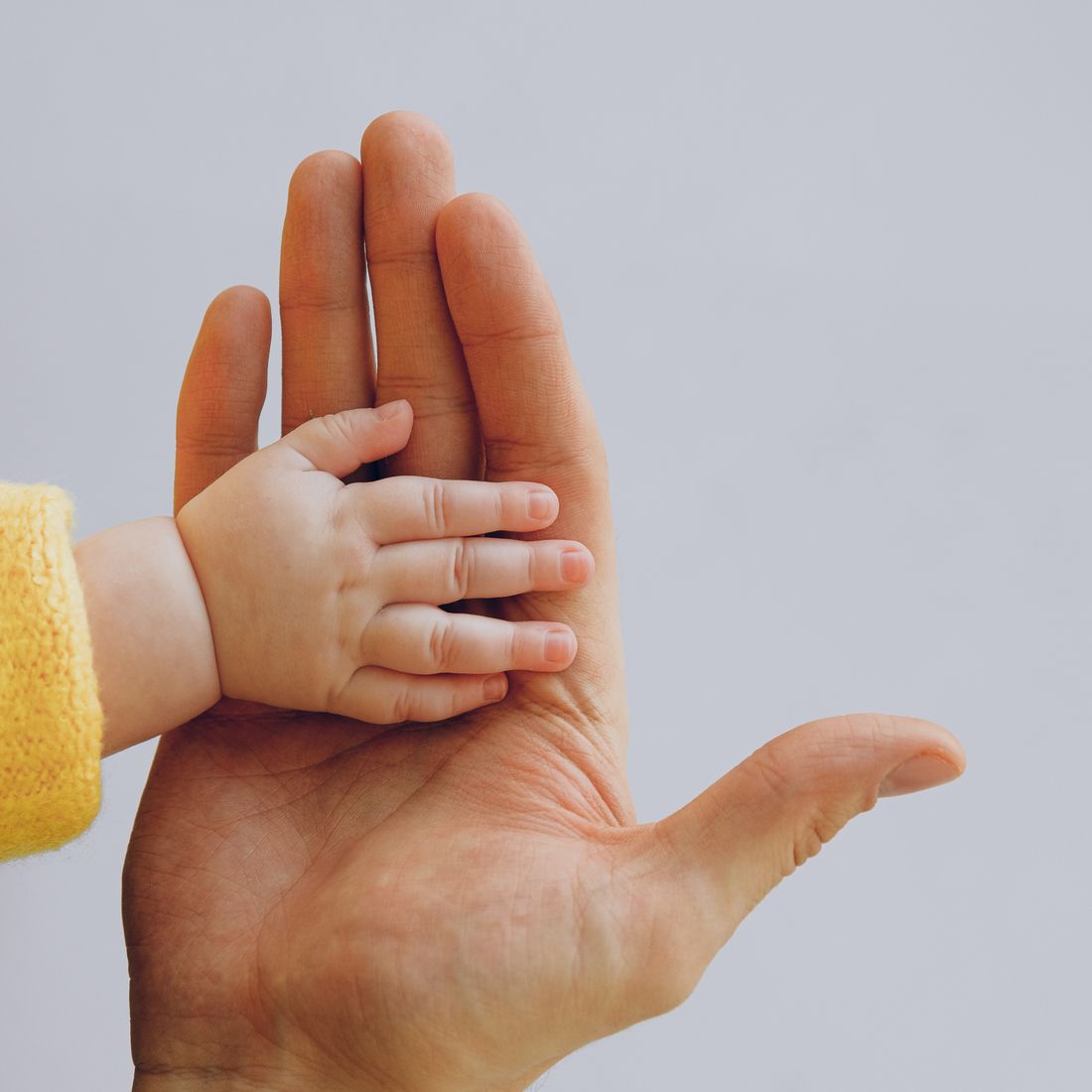 A parent's and baby's hands resting together